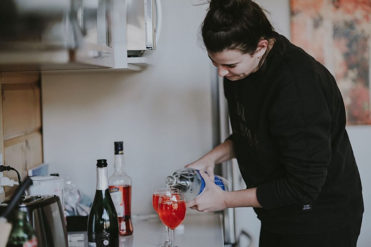 Kvinde hælder en drink i køkkenet