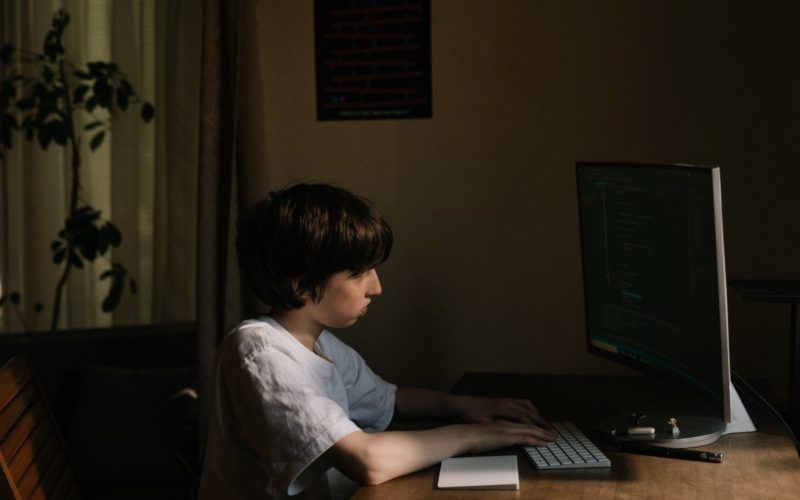 Хлапето се взира в компютъра, загрижен за кибертормоза