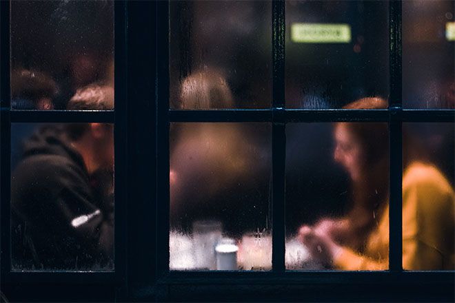Pari istuu ravintolassa sumuisilla ikkunoilla