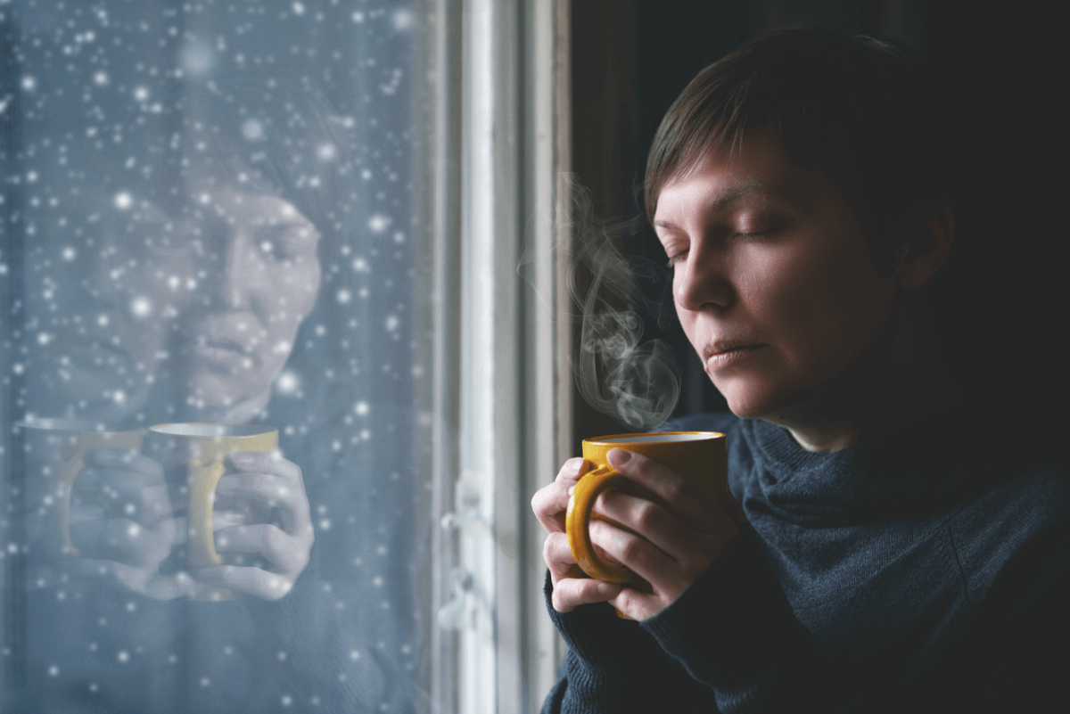 امرأة تحمل قدح القهوة أثناء الشتاء يتساقط الثلج