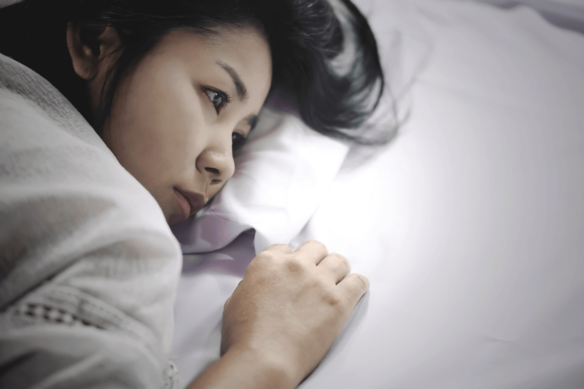 Asiatisk kvinde deprimeret i sengen