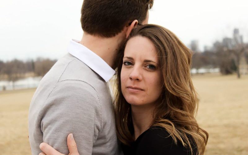 γυναίκα που αγκαλιάζει άντρα σύντροφο κοιτάζοντας τυφλά προς την κάμερα