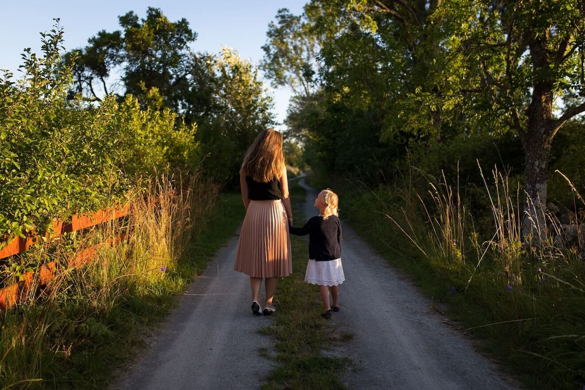 Äiti ja tytär kävelevät polulla hämärässä