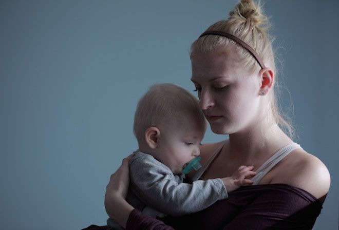 Μια μητέρα κρατά το μωρό της σε ένα δωμάτιο με χαμηλό φωτισμό