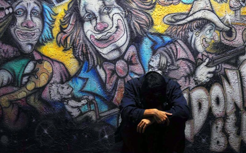 mees vaatab alla, kloun graffiti selja taga