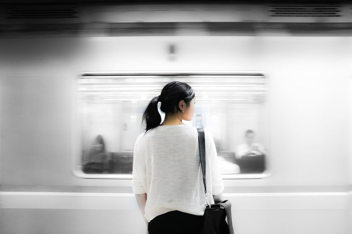 Жена у подземној железници посматра брзи воз како пролази