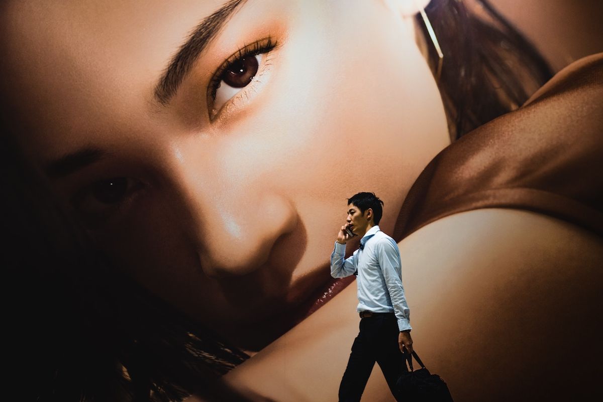 Billboard of woman towering over man on his phone