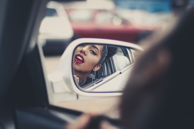 Жена, слагаща грим в огледало на кола