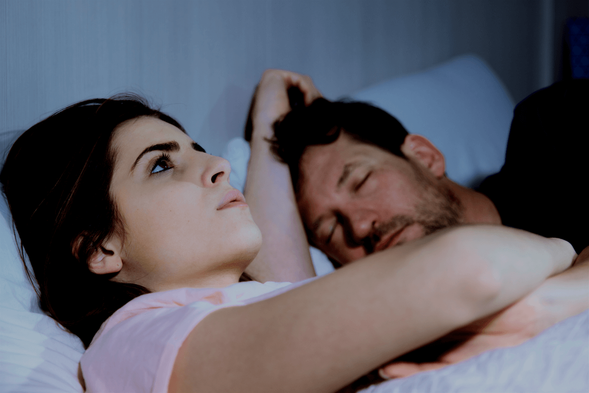 mujer en cama con marido durmiendo
