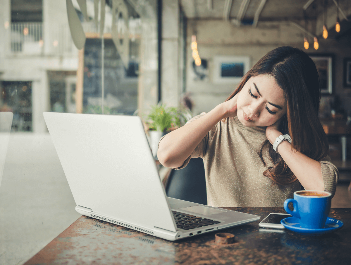 stresset øm kvinde, der arbejder på computeren på cafe