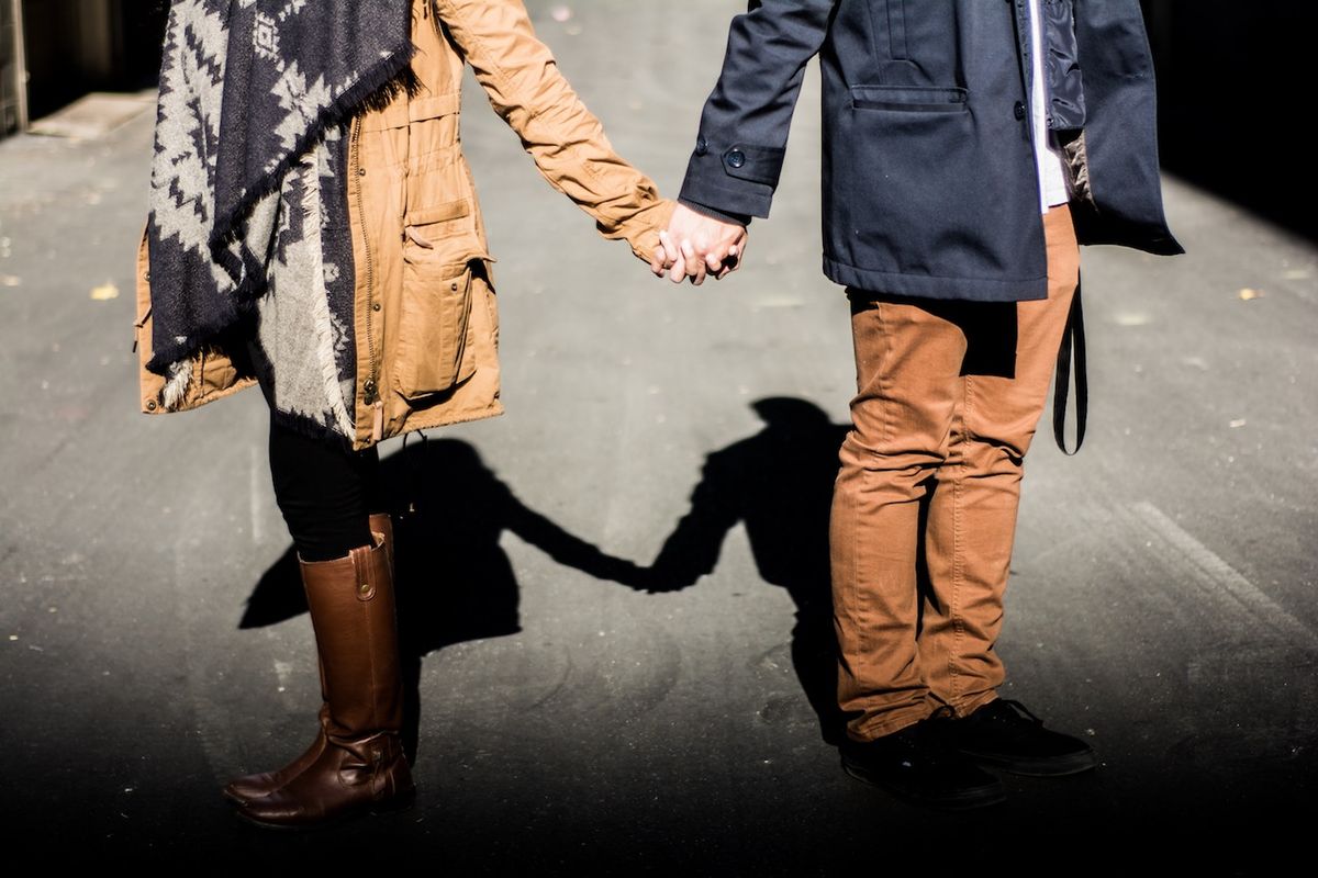 Двойка, държаща се за ръце на улицата