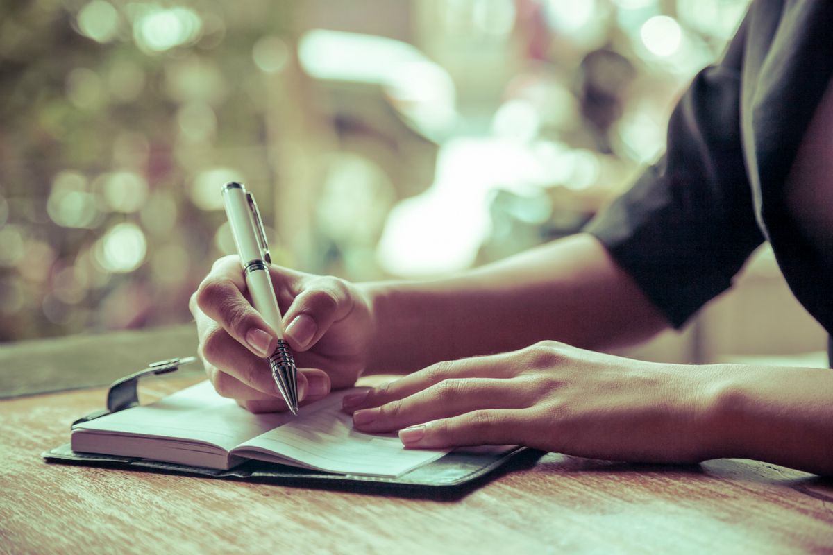 mujer escribiendo pluma mesa diario