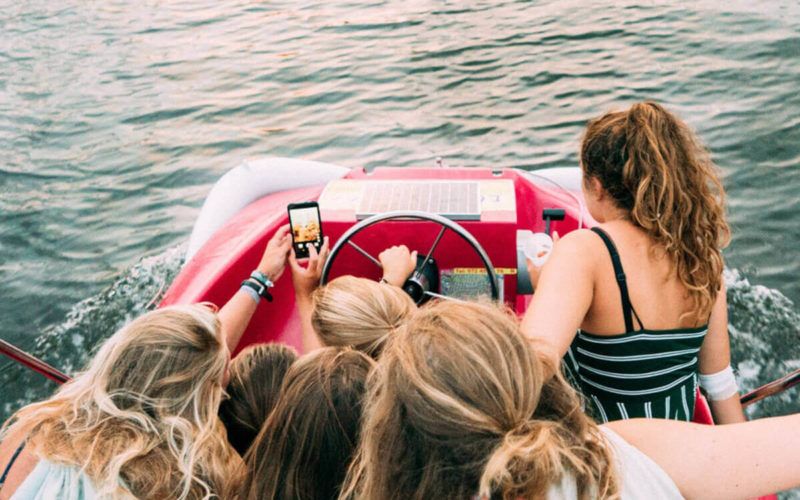 grupo de chicas en un barco mirando un teléfono