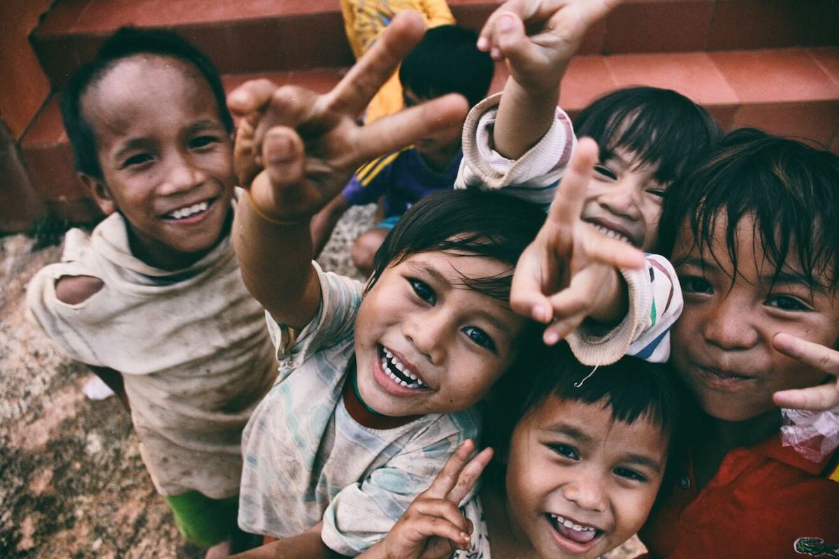 Niños sonriendo y dando el signo de la paz.